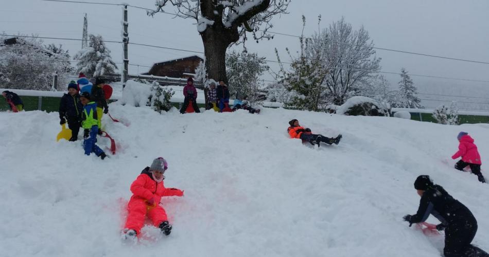 Die Kinder rutschen und spielen im Schnee